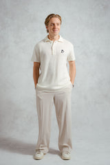 Man wearing a white polo shirt and pants on a plain background