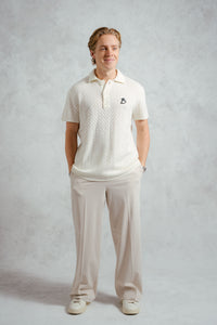 Man wearing a white polo shirt and pants on a plain background