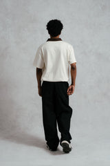 Person wearing a white shirt and black pants against a plain background