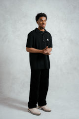 Person wearing a black polo shirt with a logo on a gray background