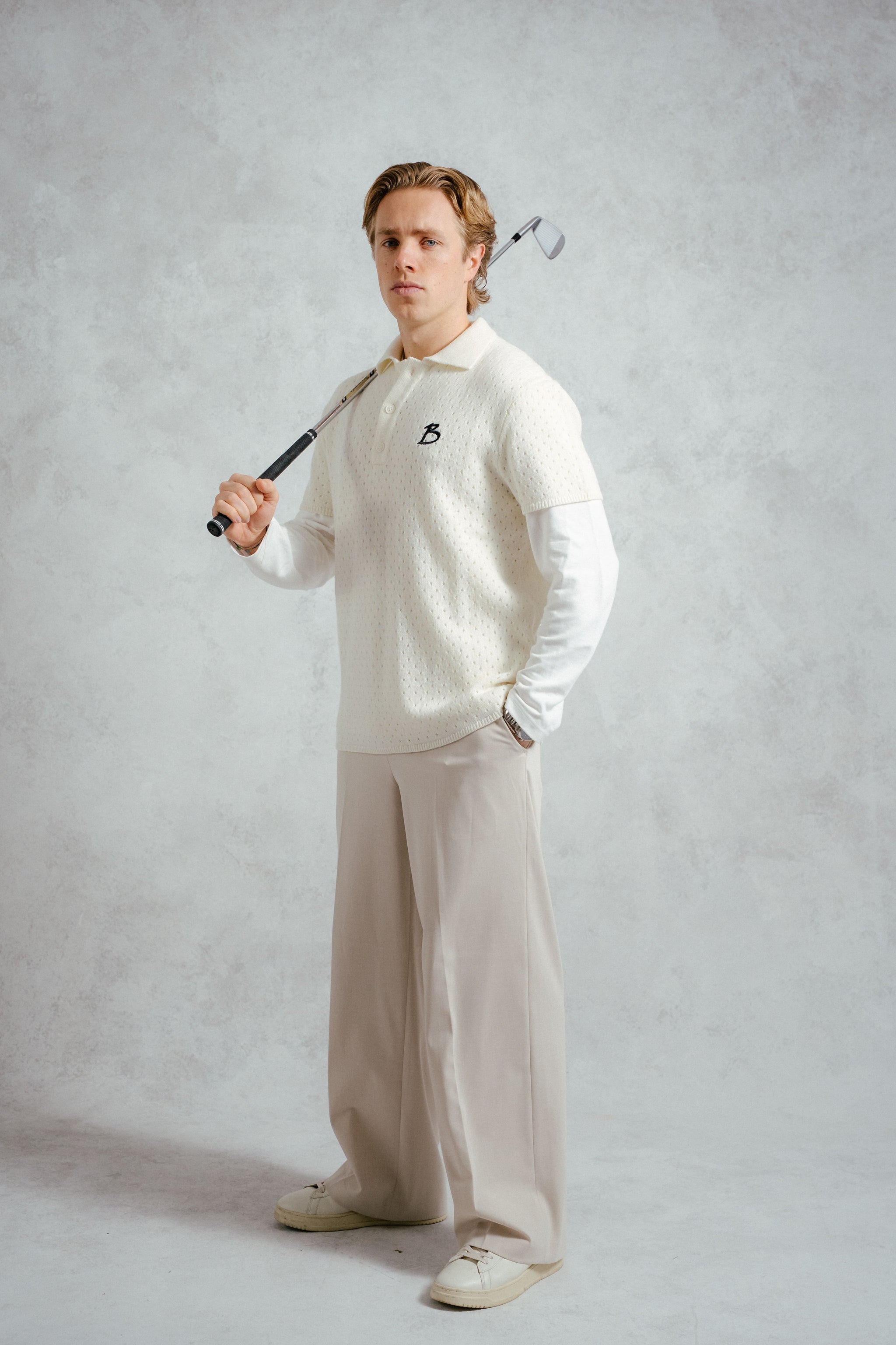 Man holding a golf club against a plain background